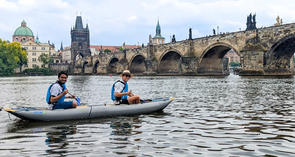 tourists on kayak on the Vltava river, Charles Bridge in the background